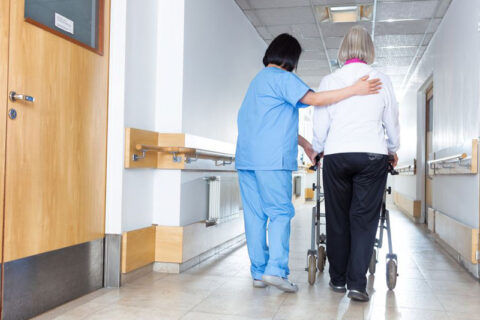 A nurse guides two women down a hallway, highlighting a scene of collaboration and care in a healthcare setting.