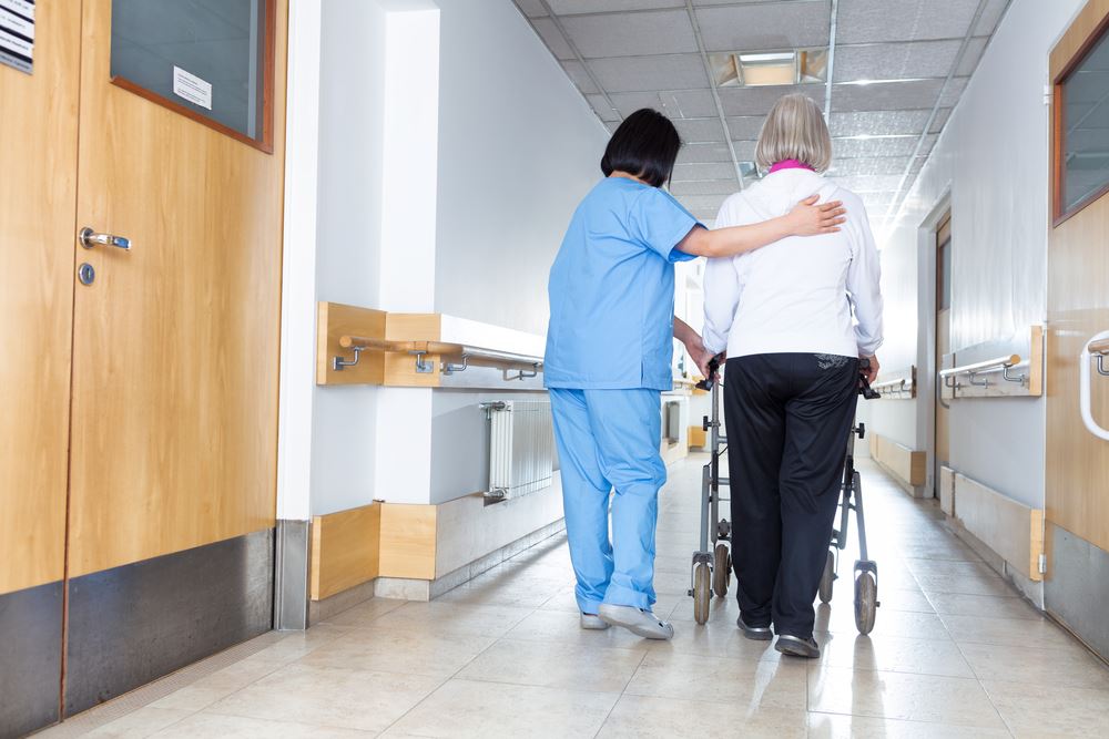 A nurse guides two women down a hallway, highlighting a scene of collaboration and care in a healthcare setting.